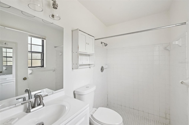 full bathroom featuring vanity, a tile shower, and toilet