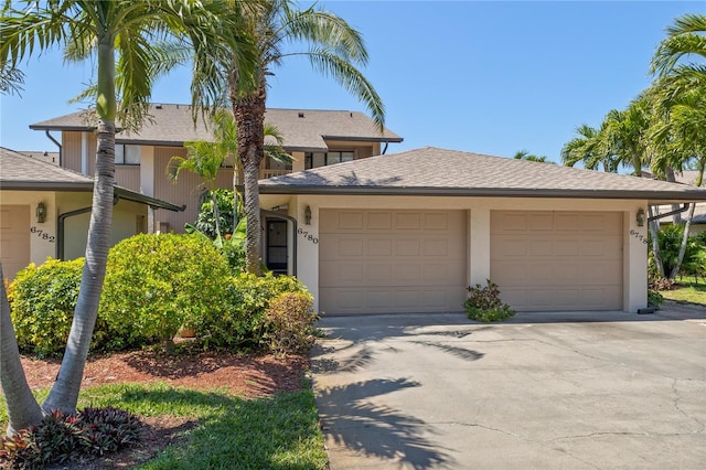 6780 Schooner Bay Cir Unit 6780, Sarasota, FL 34231 - view of front of home with an attached garage, a shingled roof, stucco siding, and concrete driveway