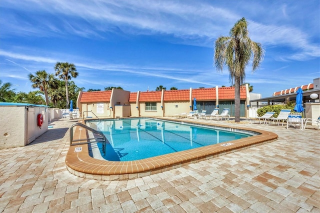 community pool with a patio and fence