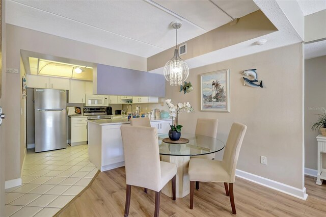 845 Benjamin Franklin Dr Unit 101, Sarasota, FL 34236 - dining area featuring light wood-style flooring, visible vents, baseboards, and a notable chandelier