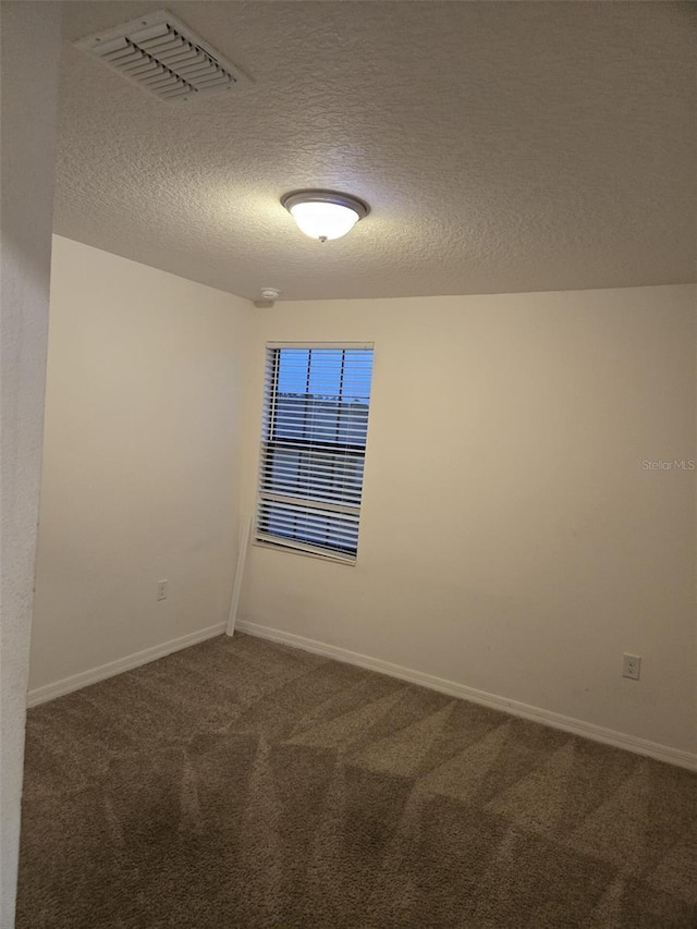 unfurnished room with carpet, visible vents, baseboards, and a textured ceiling