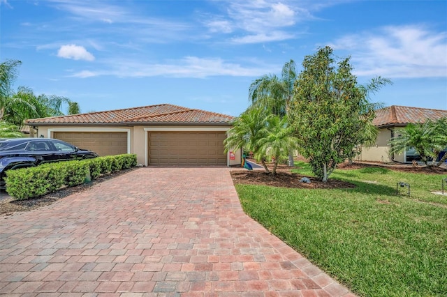 mediterranean / spanish house featuring stucco siding, an attached garage, a tiled roof, and decorative driveway
