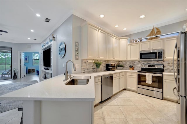 kitchen with a peninsula, crown molding, stainless steel appliances, and a sink
