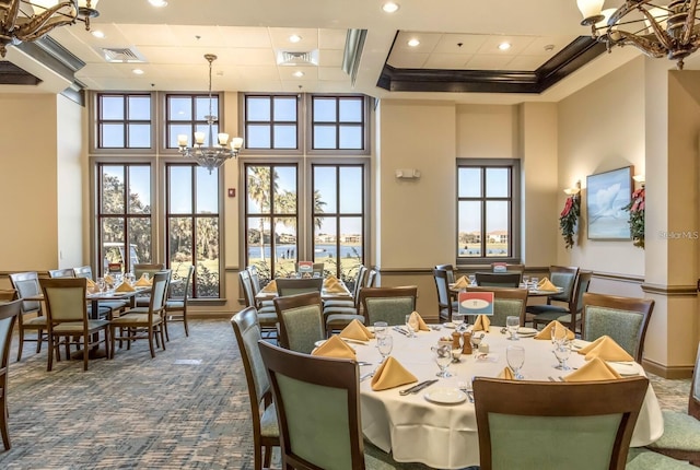 carpeted dining area featuring an inviting chandelier, coffered ceiling, a high ceiling, visible vents, and recessed lighting