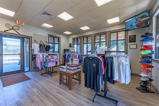 interior space featuring baseboards, wood finished floors, a drop ceiling, and visible vents
