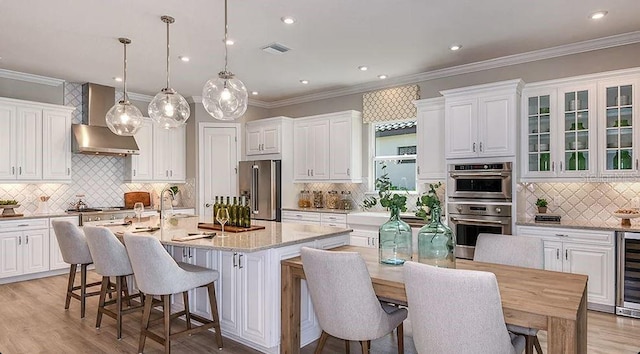 kitchen with a breakfast bar, stainless steel appliances, backsplash, white cabinetry, and visible vents