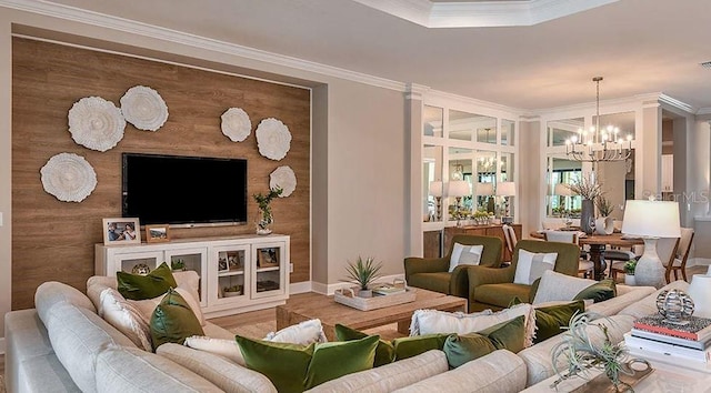 living area with wood finished floors, baseboards, a notable chandelier, and ornamental molding