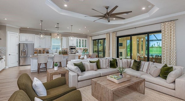 living area featuring ornamental molding, a ceiling fan, light wood-style floors, and recessed lighting