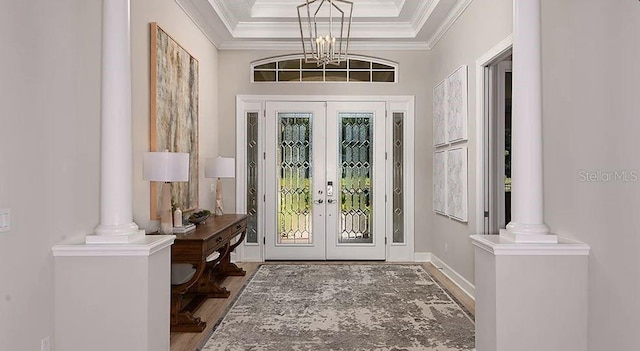 foyer with a notable chandelier, crown molding, french doors, and wood finished floors