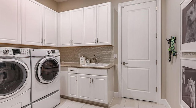 washroom with washer and clothes dryer, a sink, light tile patterned flooring, baseboards, and cabinet space
