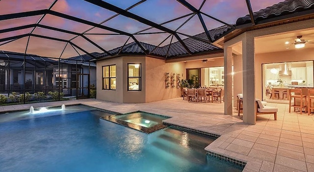 rear view of house featuring a tile roof, a patio, a pool with connected hot tub, outdoor dining area, and stucco siding