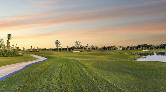 view of property's community featuring view of golf course, a water view, and a lawn