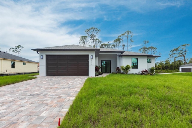 prairie-style home featuring stucco siding, decorative driveway, an attached garage, and a front lawn
