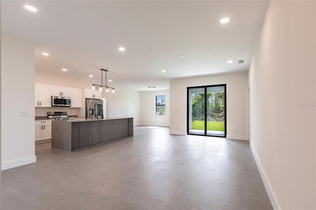kitchen featuring appliances with stainless steel finishes, open floor plan, white cabinetry, a center island with sink, and recessed lighting