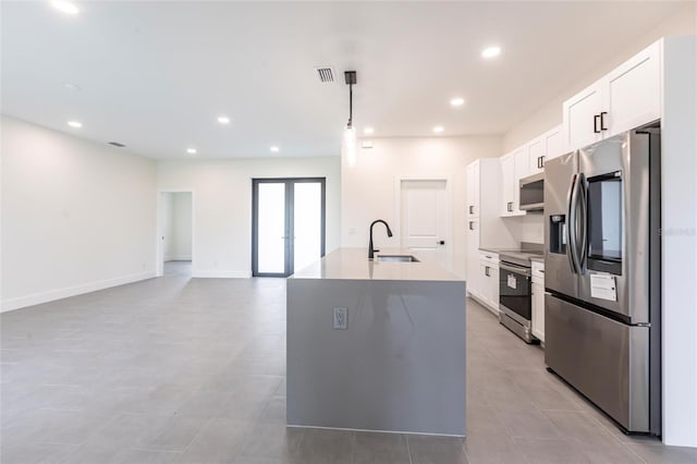 kitchen with stainless steel appliances, a sink, white cabinetry, a kitchen island with sink, and decorative light fixtures