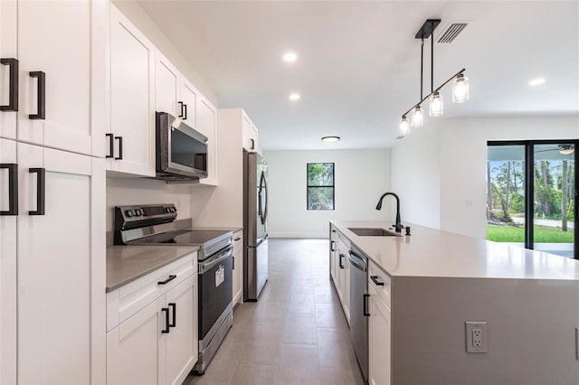 kitchen with stainless steel appliances, a sink, plenty of natural light, a center island with sink, and recessed lighting