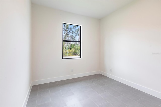 empty room with tile patterned flooring and baseboards