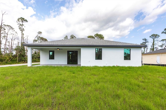 rear view of house featuring stucco siding, ceiling fan, and a yard