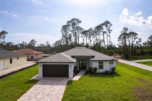 view of front of home featuring an attached garage, a front lawn, french doors, roof with shingles, and driveway