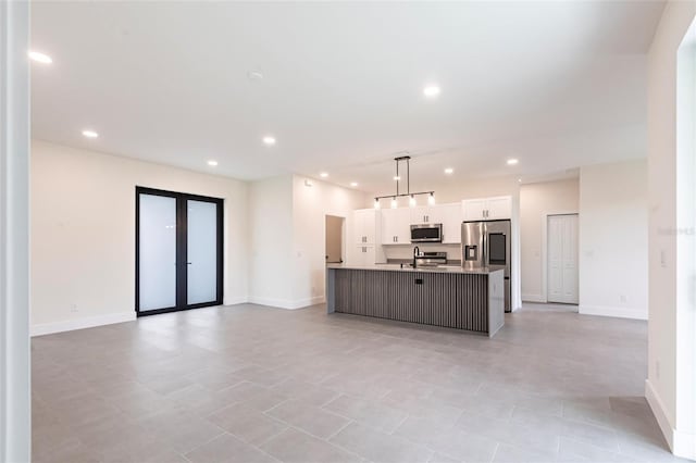 kitchen featuring stainless steel appliances, recessed lighting, white cabinetry, a center island with sink, and open floor plan