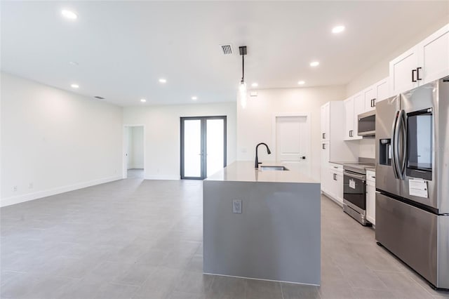 kitchen featuring stainless steel appliances, a sink, an island with sink, white cabinets, and recessed lighting