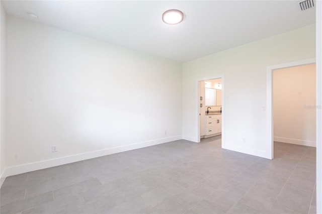 unfurnished bedroom with baseboards, ensuite bath, and a sink