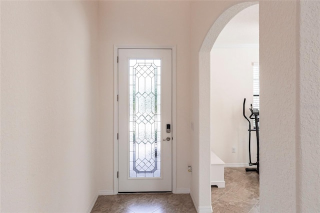entrance foyer featuring baseboards, arched walkways, and light tile patterned flooring