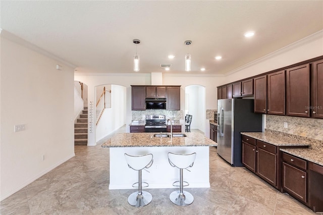 kitchen featuring dark brown cabinetry, arched walkways, a sink, and appliances with stainless steel finishes