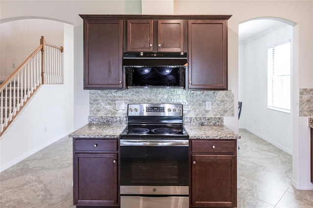 kitchen with tasteful backsplash, arched walkways, stainless steel range with electric cooktop, light stone counters, and dark brown cabinets