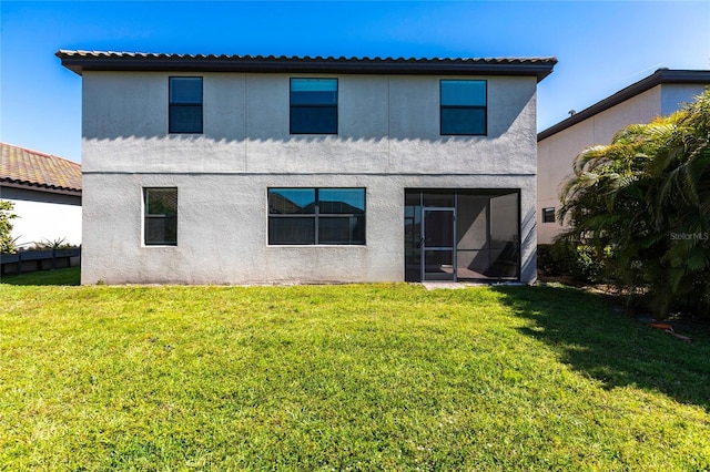 rear view of property with stucco siding, a lawn, and a sunroom