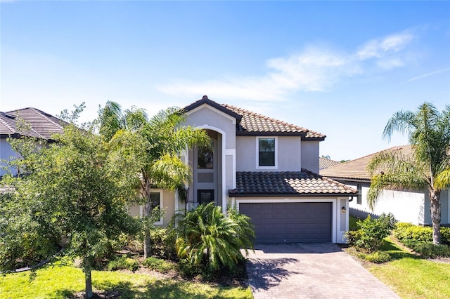 mediterranean / spanish-style house featuring a tile roof, decorative driveway, and stucco siding