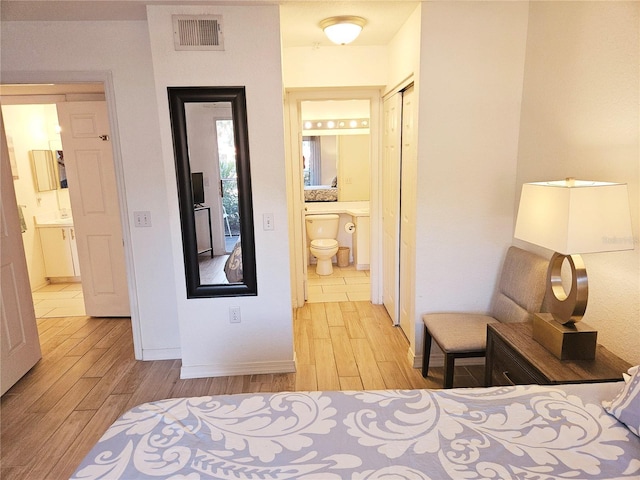 bedroom featuring light wood-type flooring, ensuite bathroom, baseboards, and a closet