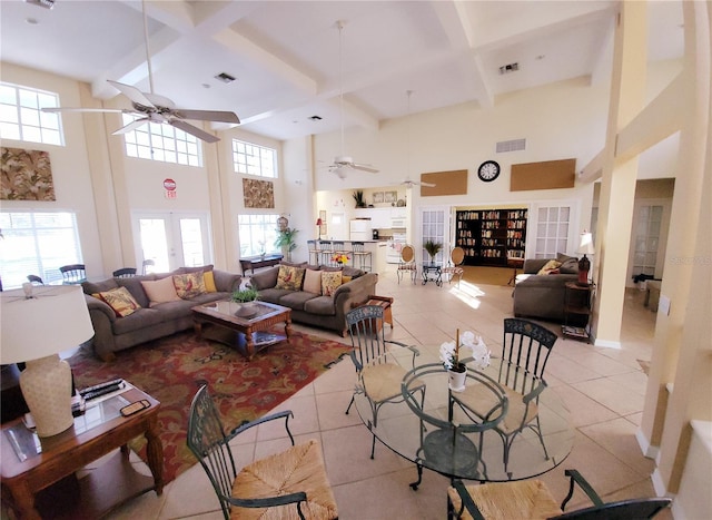 living area featuring a ceiling fan, a high ceiling, coffered ceiling, plenty of natural light, and light tile patterned floors