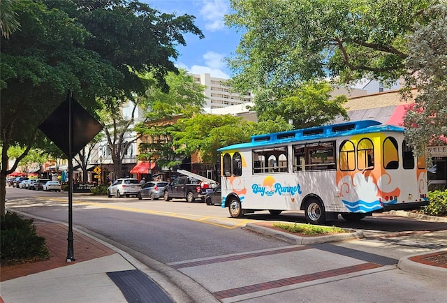 view of asphalt street featuring curbs, sidewalks, and traffic signs