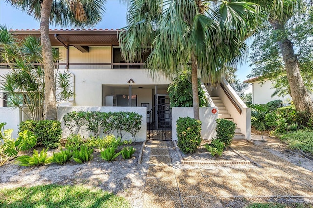 view of front facade with stucco siding, a gate, stairs, and fence private yard