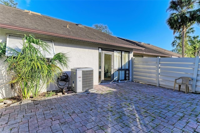 back of house with central air condition unit, fence, a patio area, and stucco siding