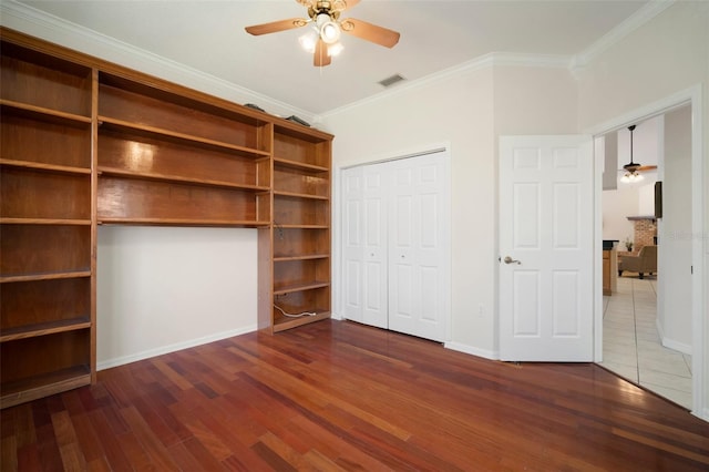 unfurnished bedroom featuring visible vents, baseboards, a ceiling fan, wood finished floors, and ornamental molding