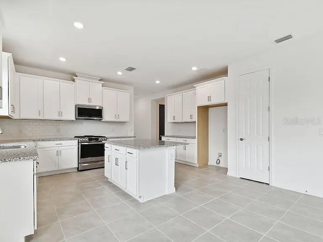 kitchen with visible vents, a sink, a center island, appliances with stainless steel finishes, and white cabinetry