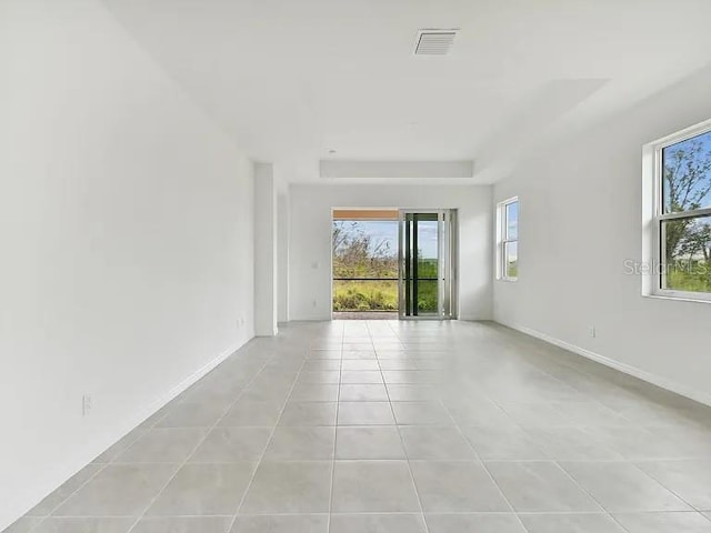 empty room with light tile patterned flooring, visible vents, and baseboards