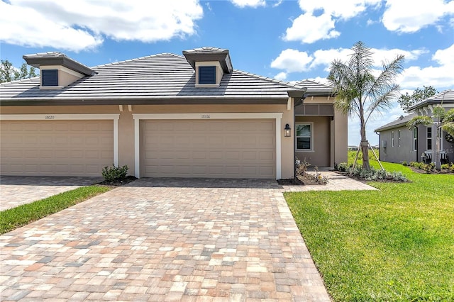multi unit property with a tile roof, a front lawn, stucco siding, and decorative driveway