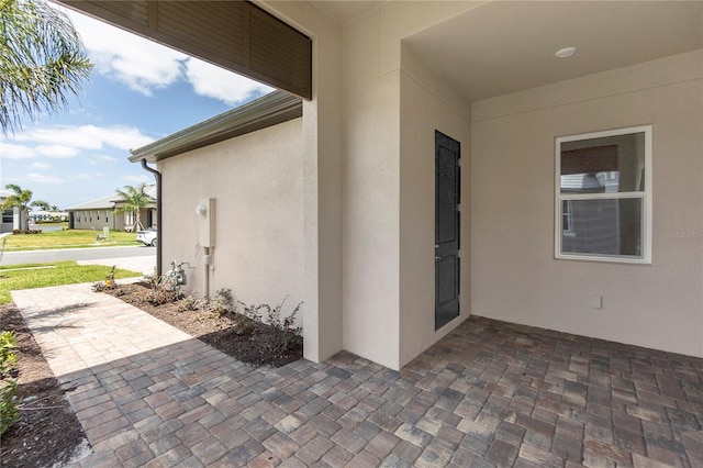 view of exterior entry featuring a patio area and stucco siding
