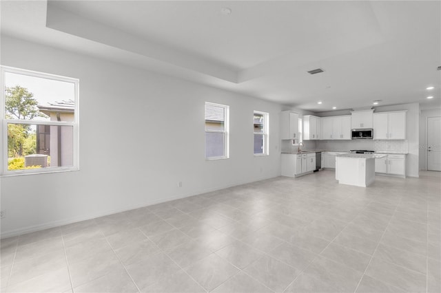 unfurnished living room featuring recessed lighting, a raised ceiling, visible vents, and baseboards