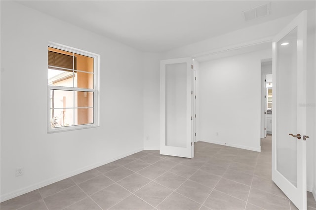 empty room with baseboards, visible vents, and light tile patterned floors