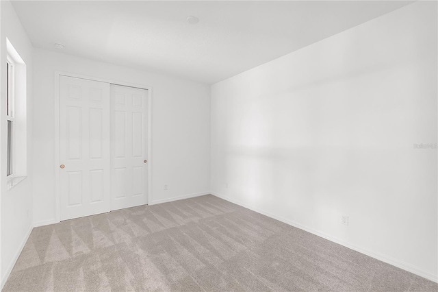 unfurnished bedroom featuring baseboards, carpet floors, and a closet