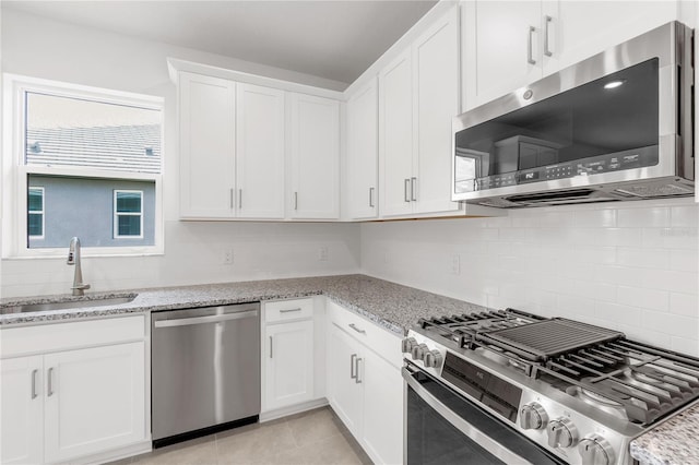kitchen with white cabinets, stainless steel appliances, a sink, and tasteful backsplash