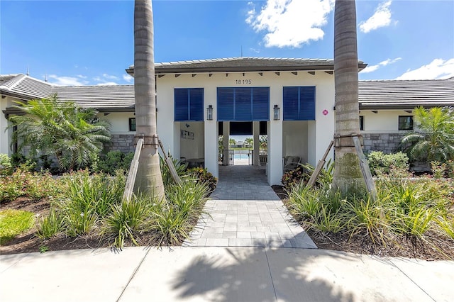 doorway to property featuring a tiled roof and stucco siding