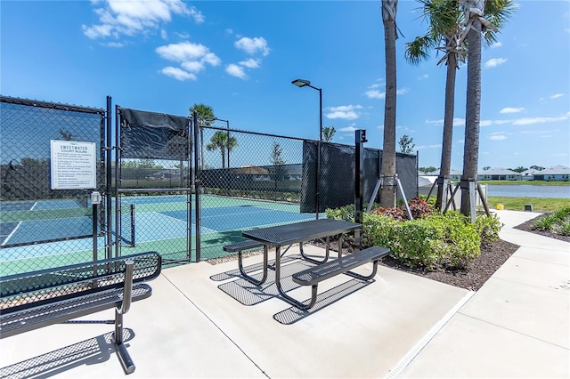 surrounding community featuring a gate, fence, and a tennis court