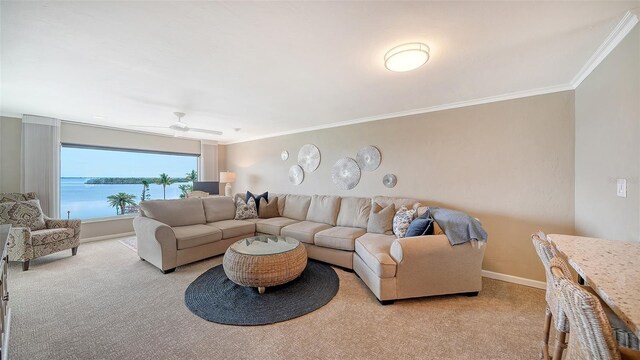 living area with light carpet, ornamental molding, baseboards, and ceiling fan