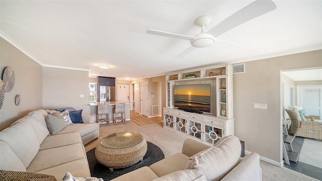 living area with ornamental molding, a ceiling fan, and baseboards