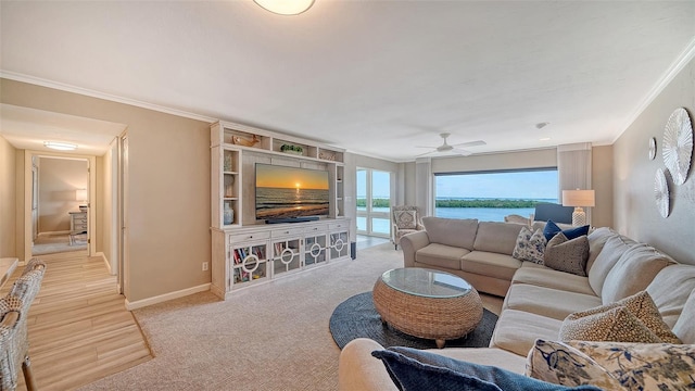 living area featuring ornamental molding, ceiling fan, baseboards, and light colored carpet